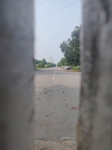 सहारा शहराच्या मागच्या दरवाजातील भेगातून रिकाम्या रस्त्याचे आणि सोडून दिलेल्या कंपनीच्या गाड्यांचे दृश्य | फोटो: अमृतांश अरोरा | द प्रिंट