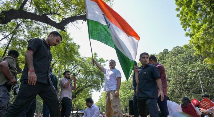 संसद भवनापासून निवडणूक आयोगाच्या कार्यालयापर्यंत 'इंडिया' आघाडीने काढलेल्या निषेध मोर्चादरम्यान, आकाशवाणी भवनाजवळ बॅरिकेडवर उभे राहून तिरंगा फडकवताना लोकसभेतील विरोधी पक्षनेते राहुल गांधी | सूरज सिंग बिष्ट | द प्रिंट